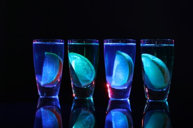 Alcohol drink with citrus wedges in shot glasses on mirror surface
