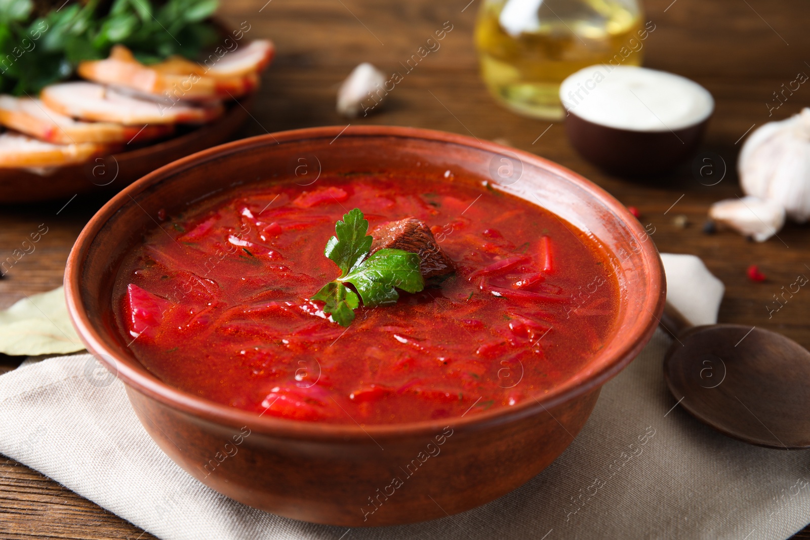 Photo of Stylish brown clay bowl with Ukrainian borsch served on wooden table, closeup
