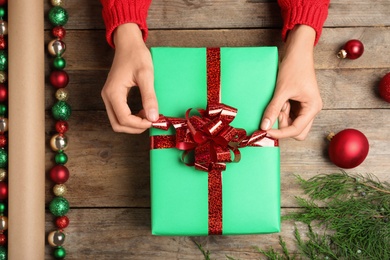 Photo of Woman wrapping Christmas gift at wooden table, top view