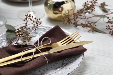 Photo of Stylish table setting with cutlery and eucalyptus leaves, closeup