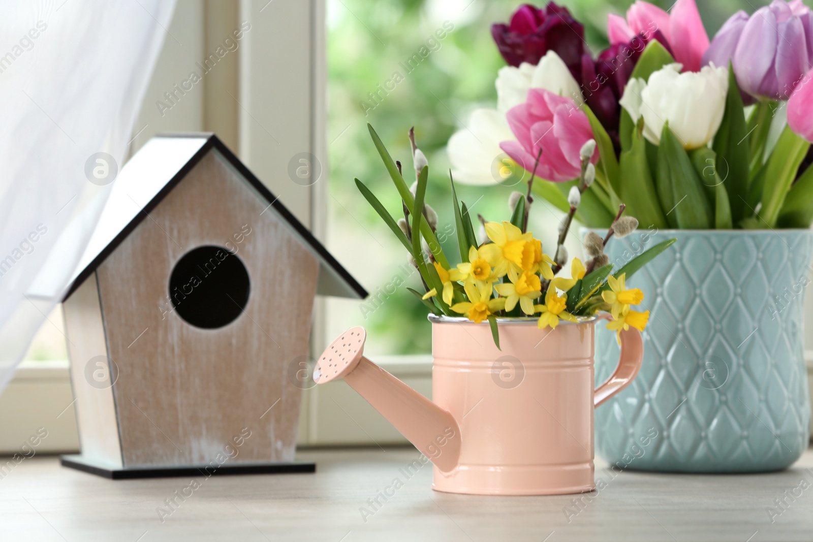 Photo of Beautiful spring flowers with birdhouse on window sill