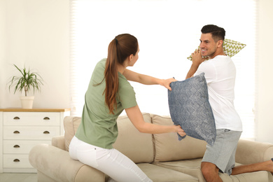 Happy couple having pillow fight in living room