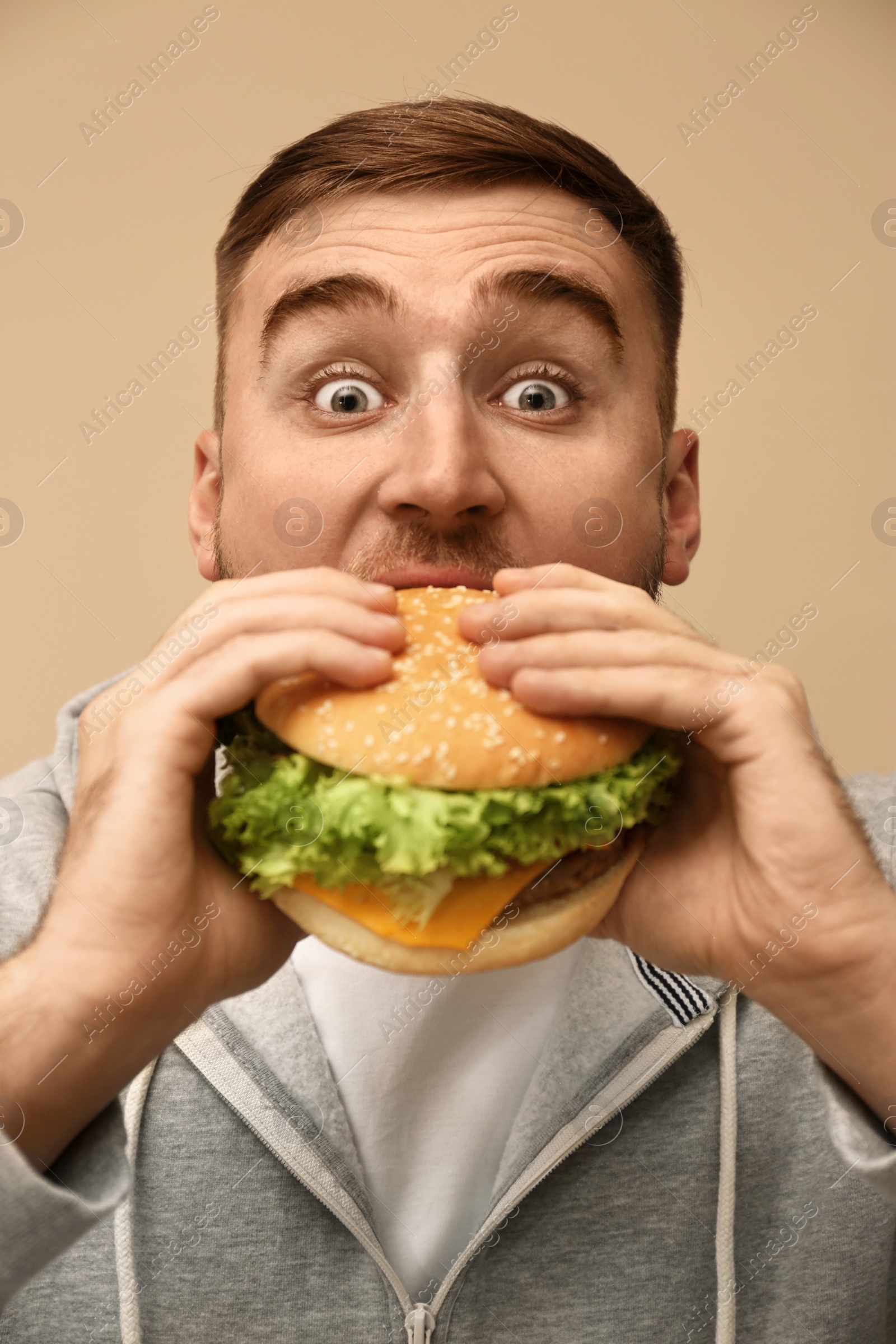 Photo of Young man eating tasty burger on color background