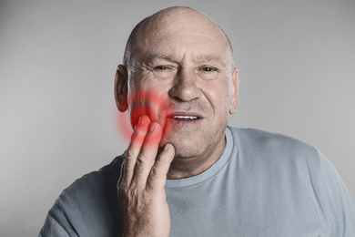 Image of Senior man suffering from toothache on grey background