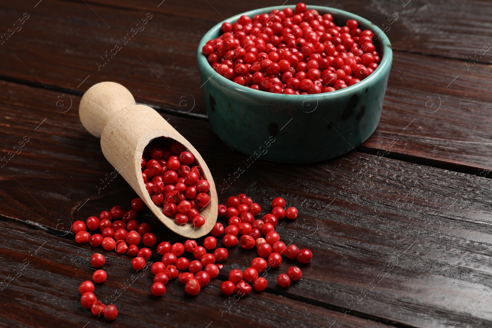 Photo of Aromatic spice. Red pepper in bowl and scoop on wooden table, closeup