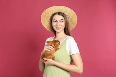Young woman with adorable rabbit on pink background. Lovely pet