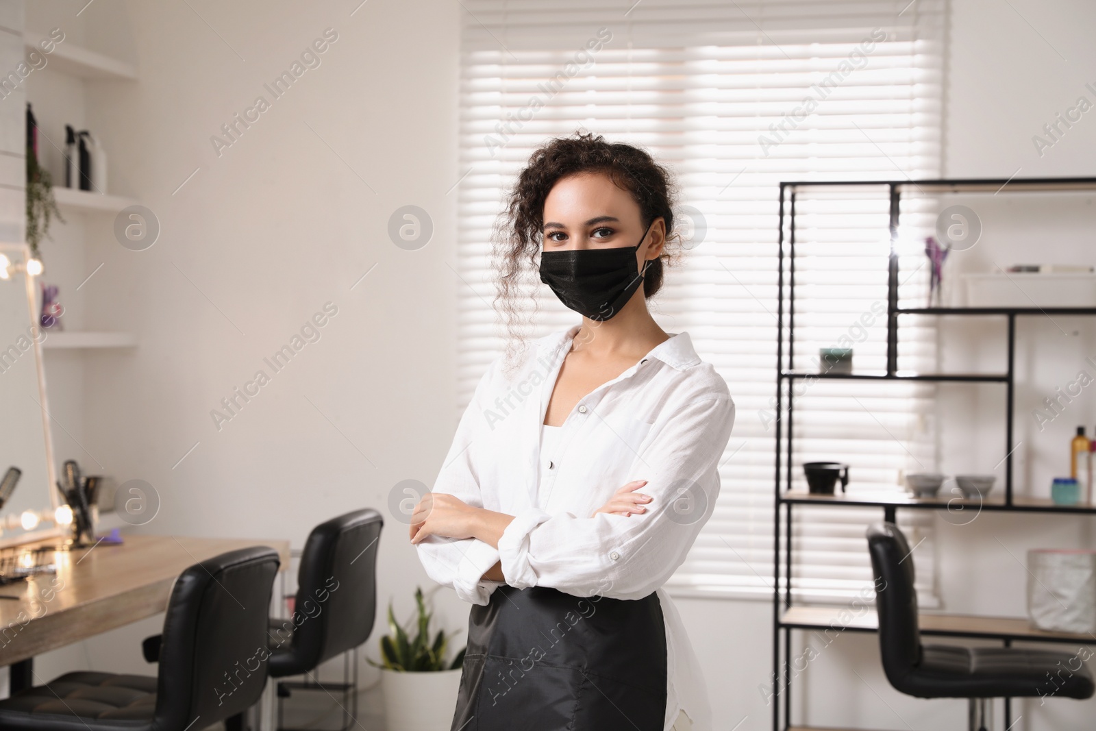 Photo of Professional stylist with protective mask in salon. Hairdressing services during Coronavirus quarantine