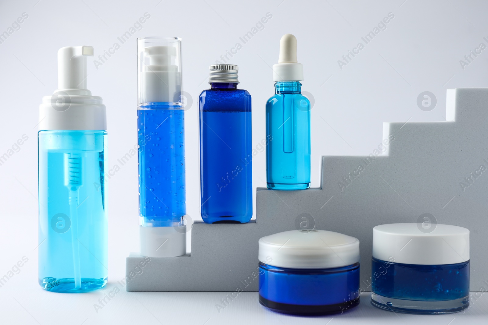 Photo of Set of luxury cosmetic products on stairs against white background