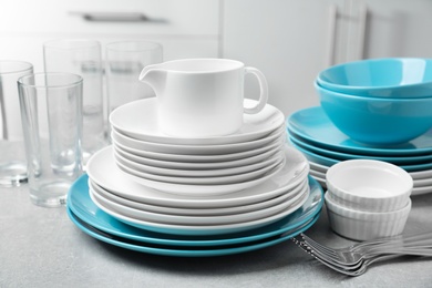 Set of clean dishes and cutlery on table in kitchen