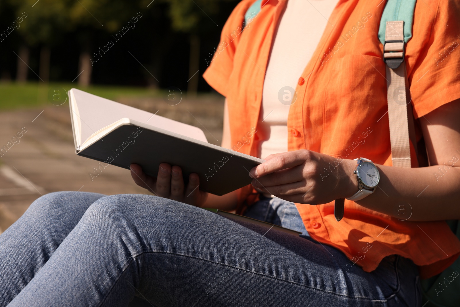 Photo of Student studying with notebook on steps outdoors, closeup