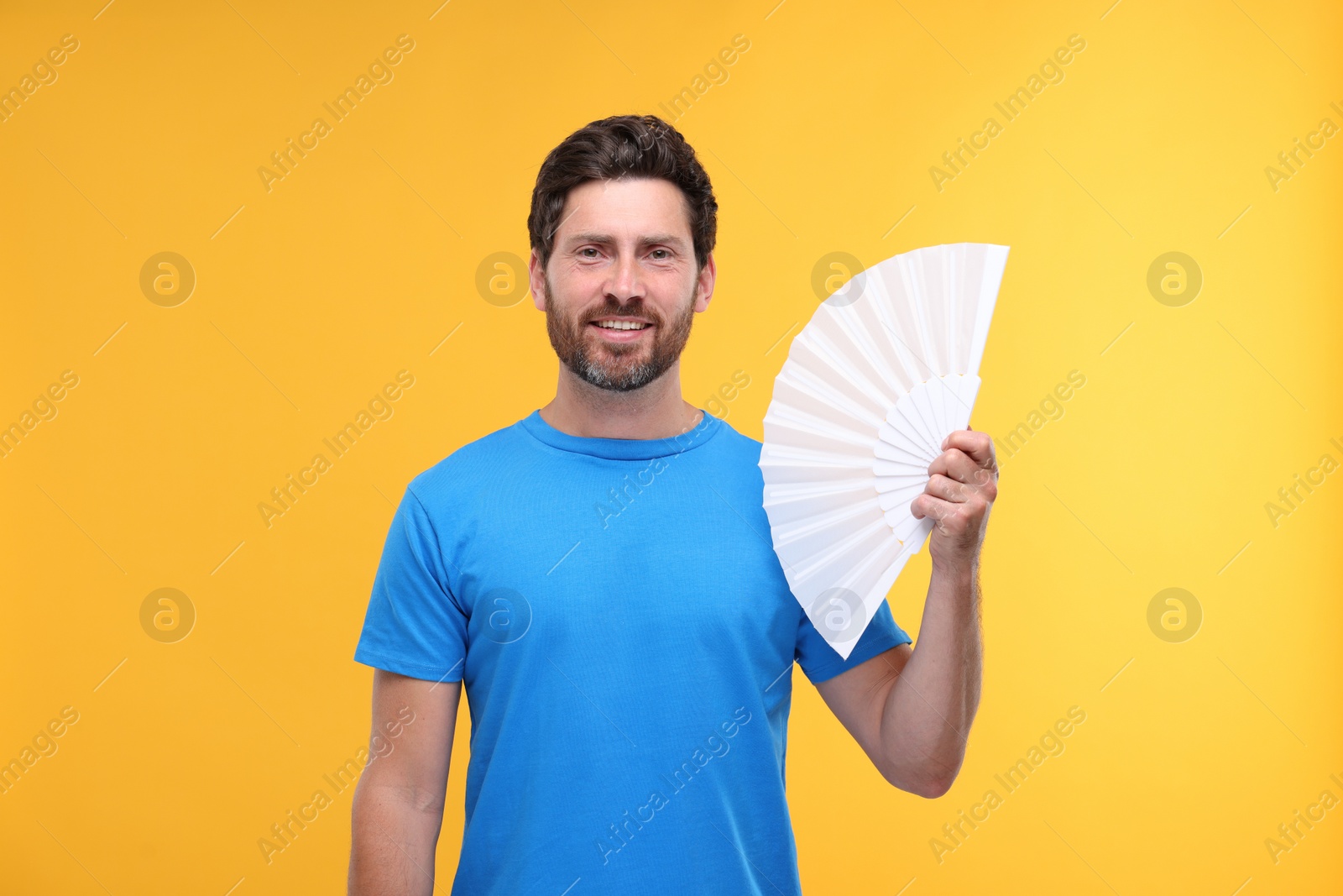 Photo of Happy man holding hand fan on orange background