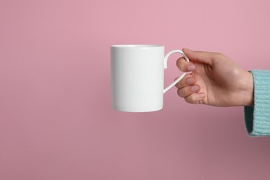 Photo of Woman holding white mug on pink background, closeup. Space for text