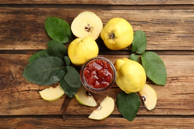 Delicious quince jam and fruits on wooden table, flat lay