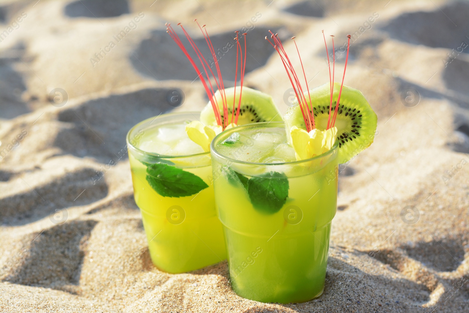 Glasses of refreshing drink with kiwi and mint on sand Photo of Glasses of refreshing drink with kiwi and mint on sand