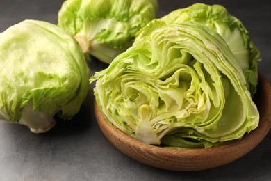 Photo of Fresh green cut and whole iceberg lettuce heads on grey table, closeup