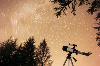 Modern telescope and beautiful sky outdoors, low angle view. Star trail