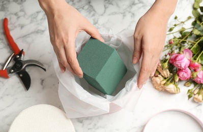 Female florist using floral foam for work at table