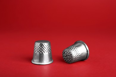 Photo of Silver thimbles on red background. Sewing accessory
