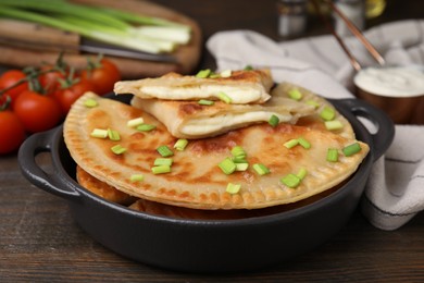 Photo of Delicious fried chebureki with cheese and green onion on wooden table