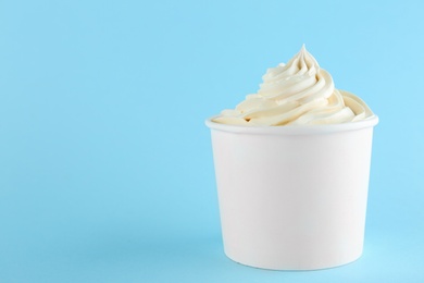 Photo of Cup with tasty frozen yogurt on blue background. Space for text