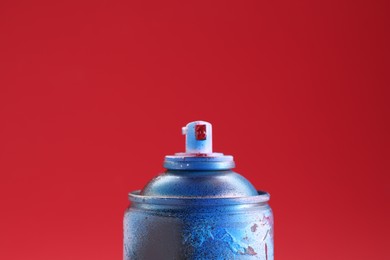 Photo of One can of bright spray paint on red background, closeup