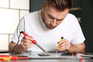 Technician repairing mobile phone at table in workshop