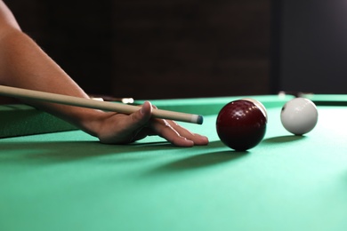 Photo of Young man playing Russian billiard indoors, closeup