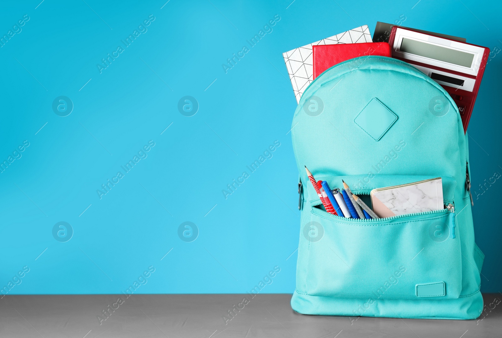 Photo of Stylish backpack with different school stationery on table against light blue background. Space for text