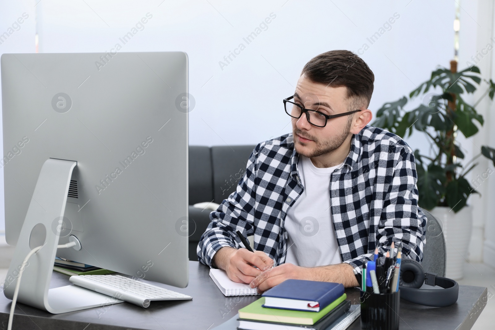 Photo of Young man using modern computer for studying at home. Distance learning