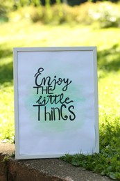 Photo of Poster with phrase Enjoy The Little Things on grass outdoors