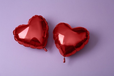 Photo of Red heart shaped balloons on violet background, flat lay. Saint Valentine's day celebration