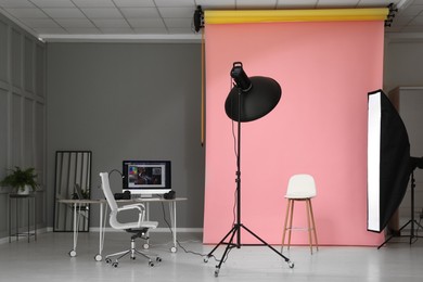 Photo of Pink photo background, workplace and professional lighting equipment in modern studio