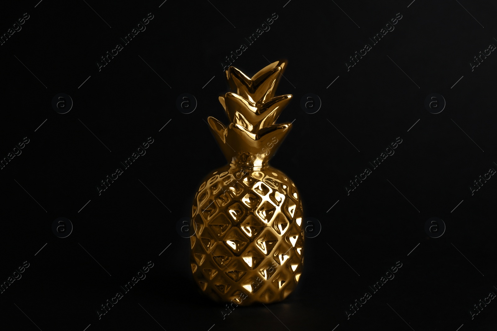Photo of Gold metal decorative pineapple on black background