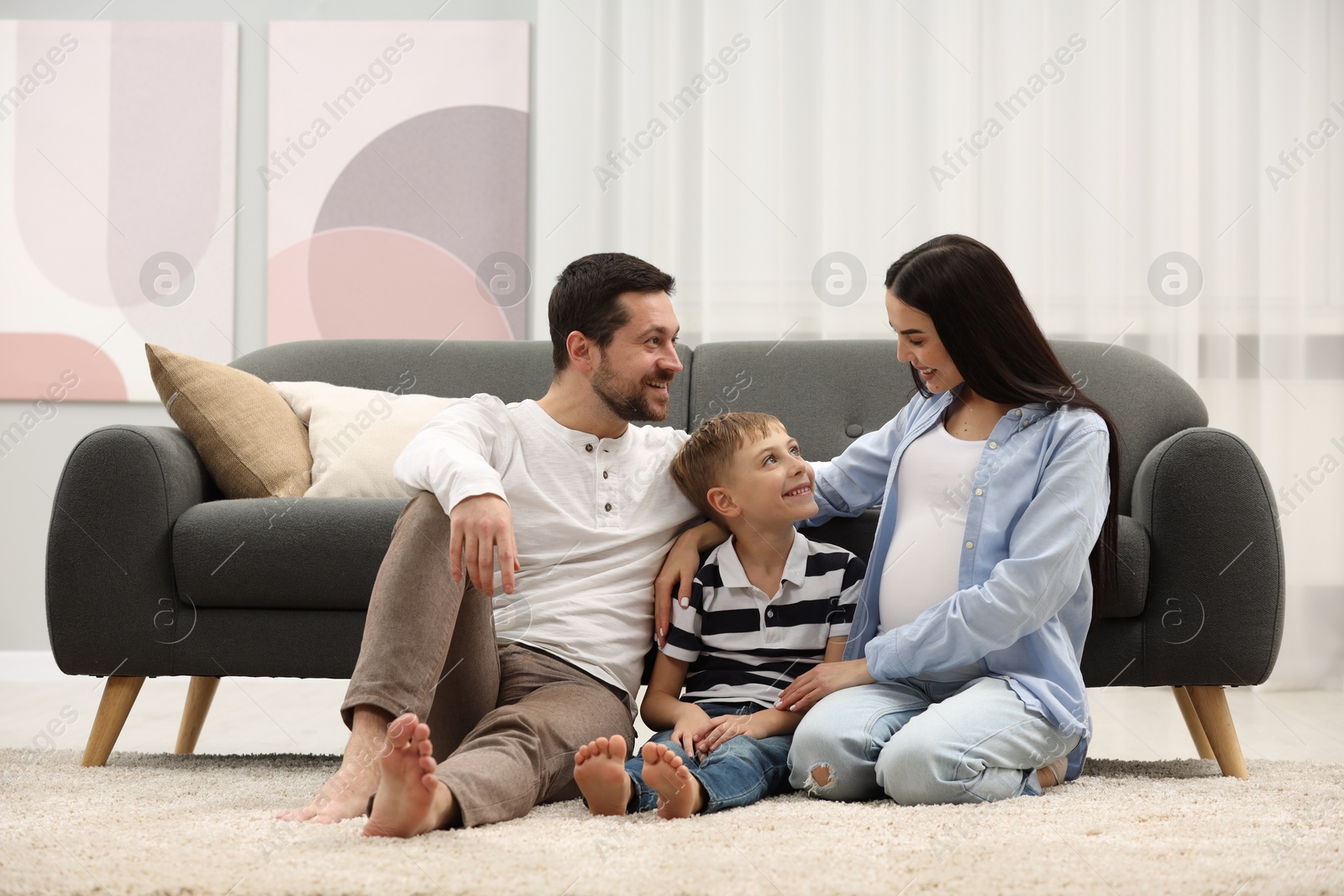 Photo of Pregnant woman spending time with her son and husband at home. Happy family