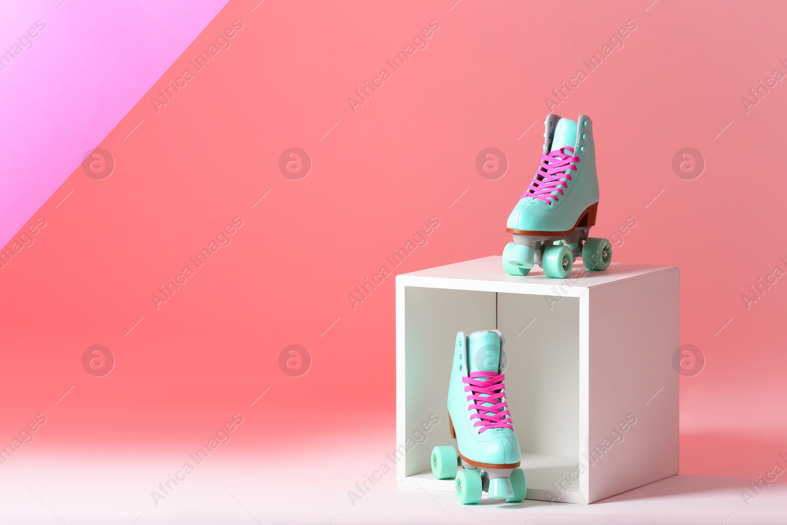 Photo of Pair of vintage roller skates and storage cube on color background. Space for text