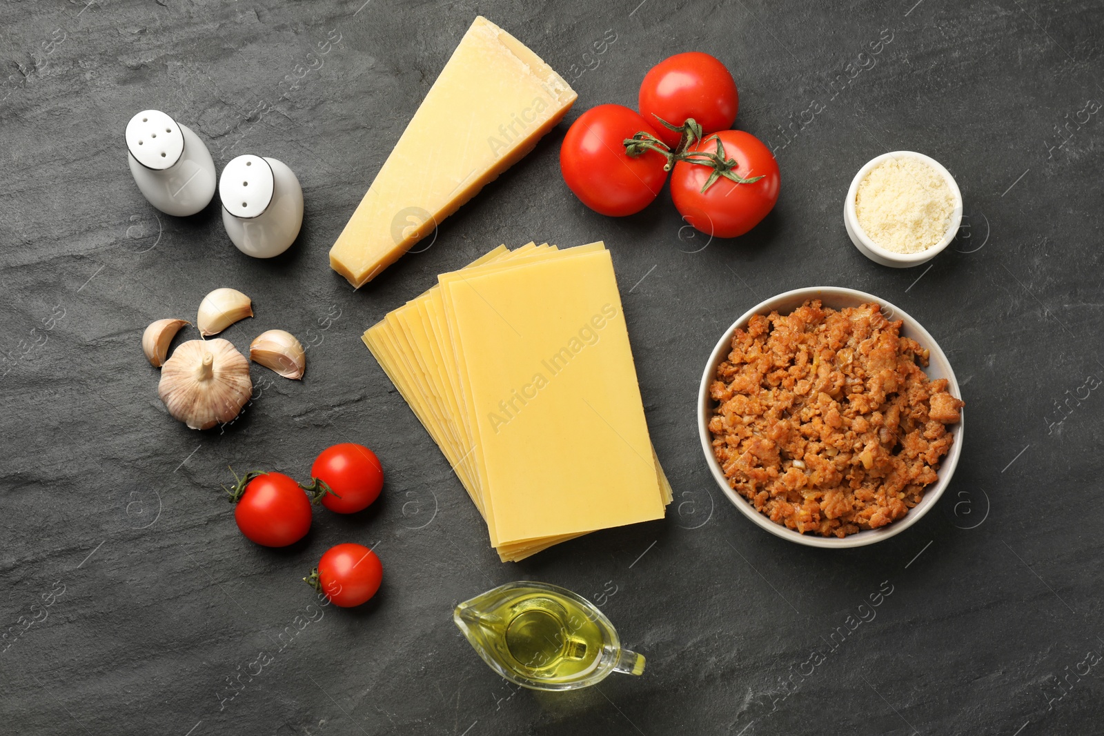 Photo of Flat lay composition with products for cooking lasagna on dark textured table