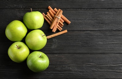 Photo of Fresh apples and cinnamon sticks on wooden table