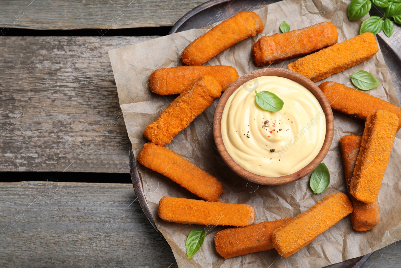 Photo of Delicious chicken nuggets and cheese sauce with basil on wooden table, top view