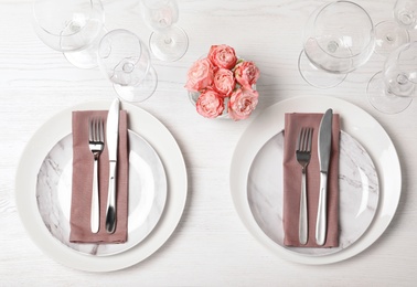 Festive table setting with plates, cutlery and napkins on wooden background, flat lay