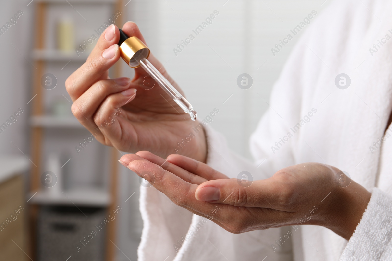 Photo of Woman applying cosmetic serum onto her hand indoors, closeup