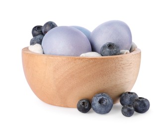 Photo of Colorful Easter eggs painted with natural dye and fresh blueberries on white background