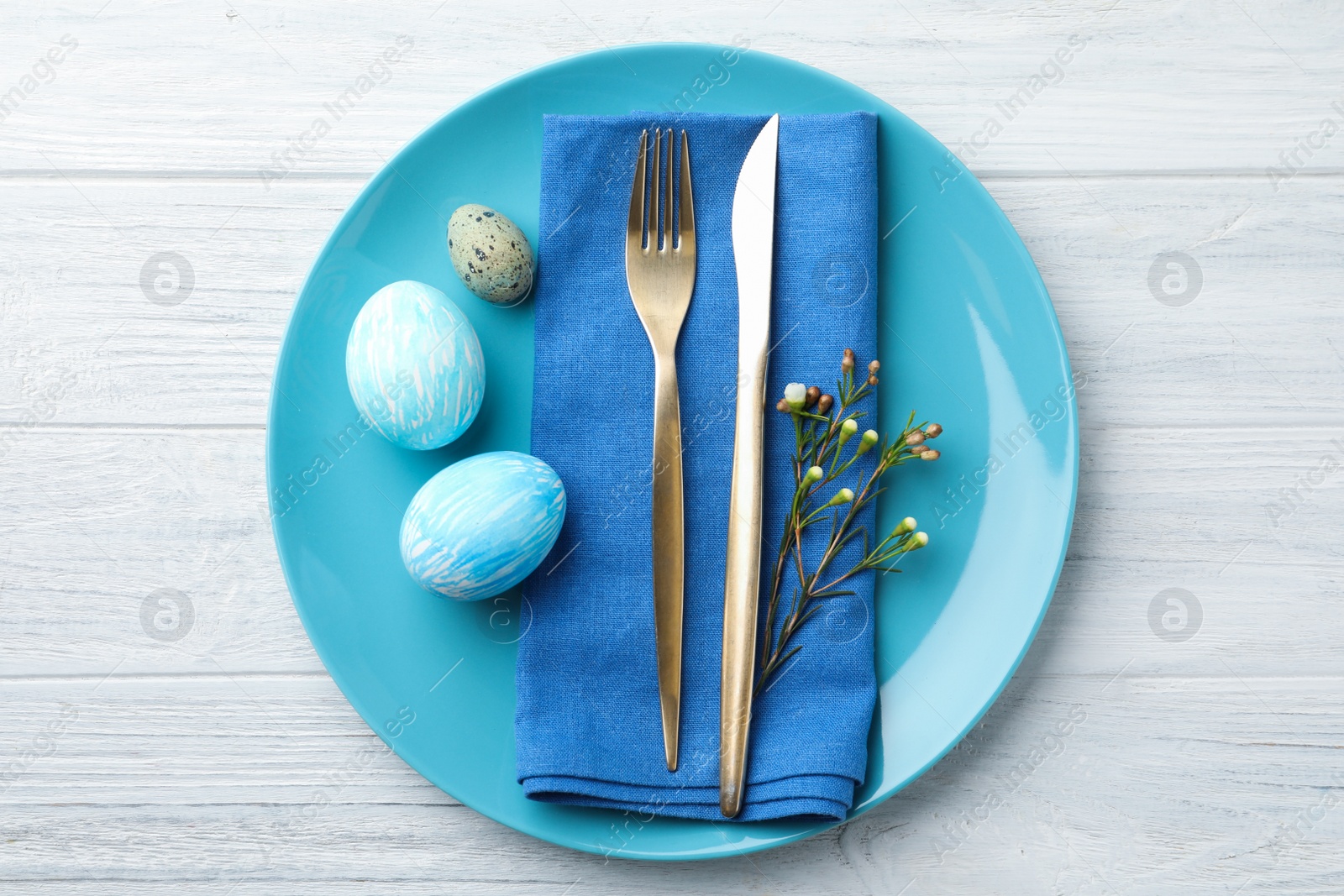 Photo of Festive Easter table setting with eggs and floral decoration on wooden background, flat lay