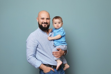 Portrait of dad and his little son on color background