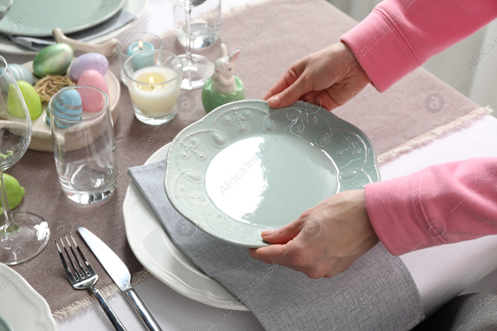 Photo of Woman setting table for festive Easter dinner at home, closeup