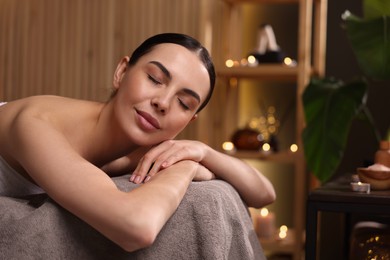 Photo of Spa therapy. Beautiful young woman lying on massage table in salon, space for text