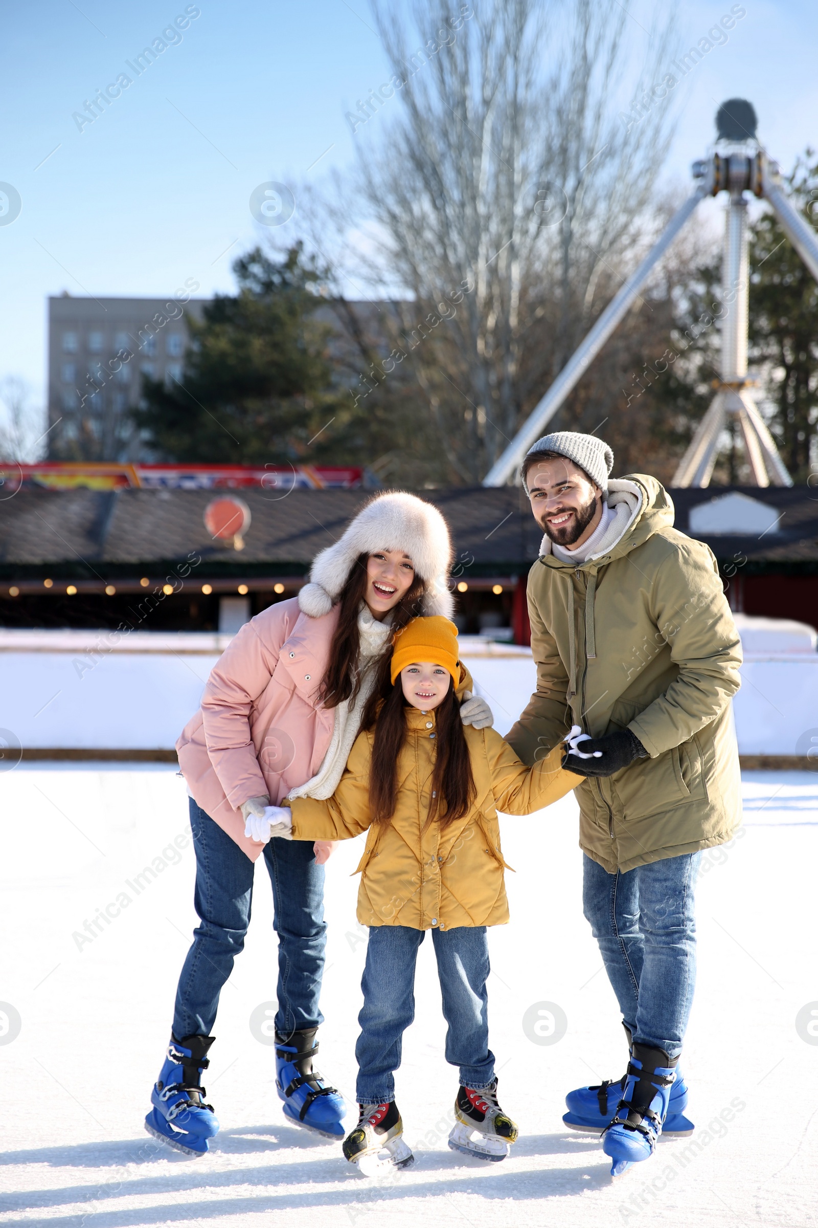 Image of Happy family spending time together at outdoor ice skating rink