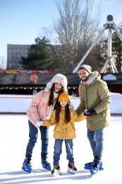 Happy family spending time together at outdoor ice skating rink