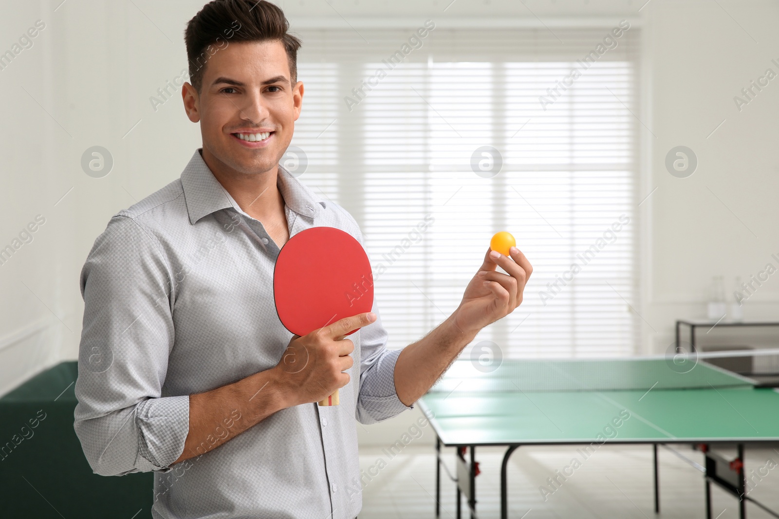 Photo of Businessman with tennis racket and ball near ping pong table in office. Space for text