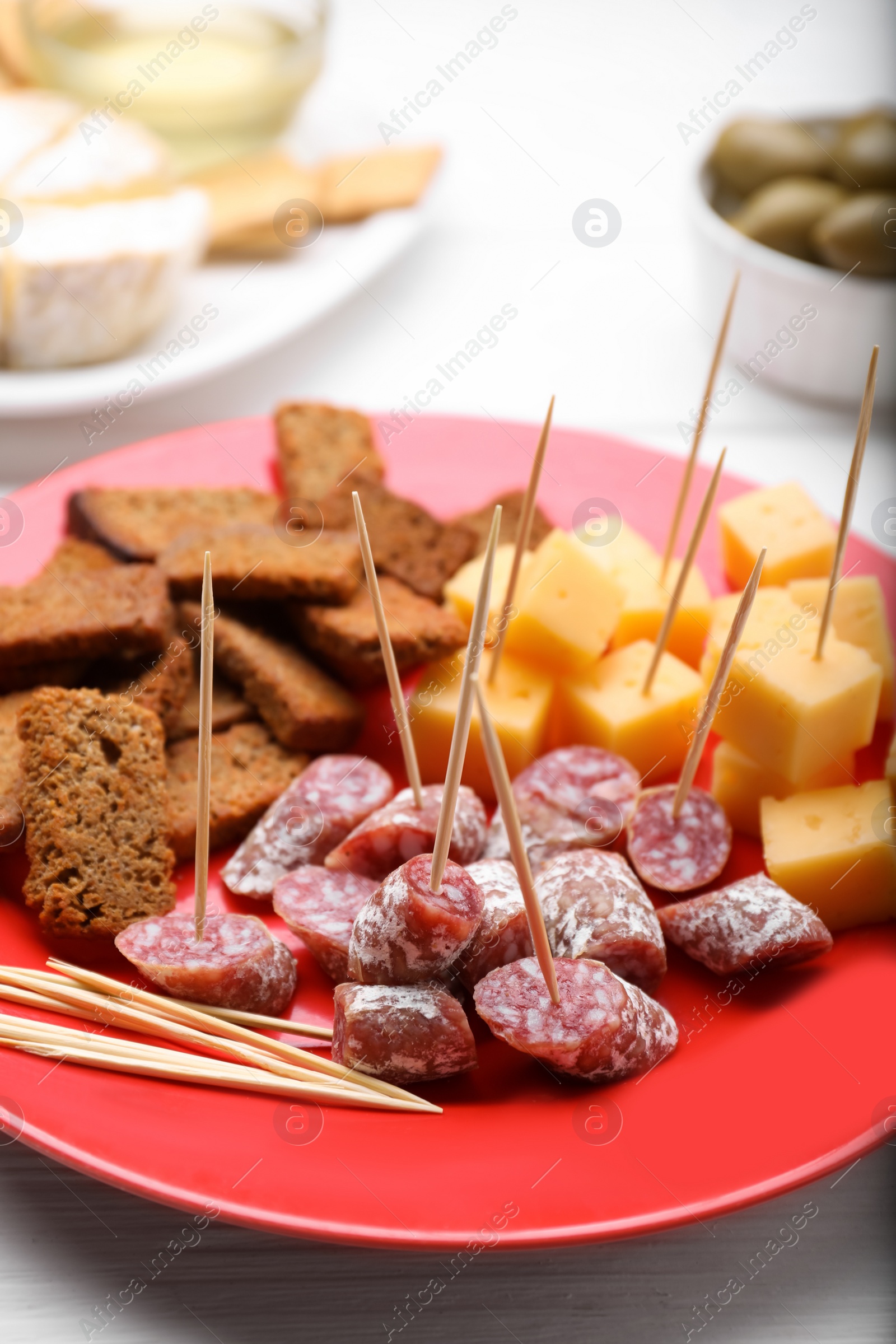 Photo of Toothpick appetizers. Pieces of cheese and croutons on red plate