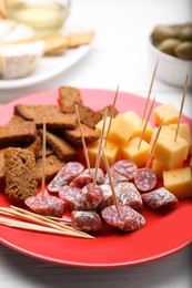 Photo of Toothpick appetizers. Pieces of cheese and croutons on red plate